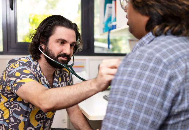 A clinician using a stethoscope to examine a patient